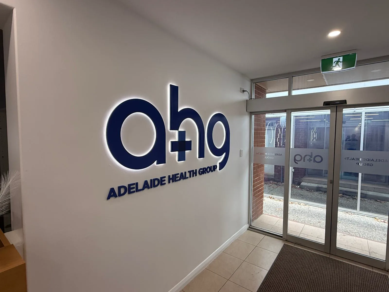 The illuminated Adelaide Health Group sign in the foyer at the Torrensville clinic entrance