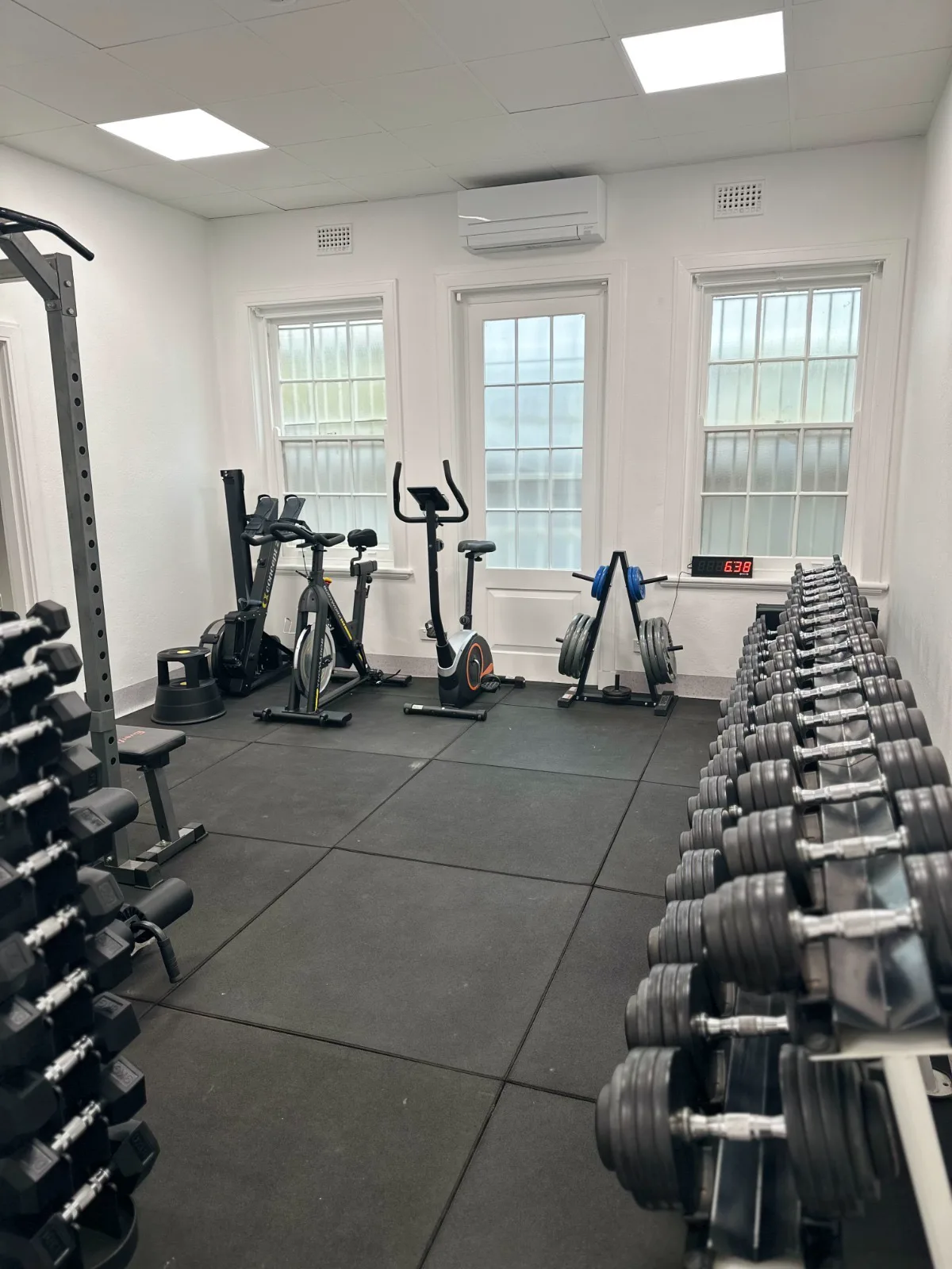 The exercise room at Adelaide Health Group, with exercise bikes, weight plates and a long rack of dumbbells