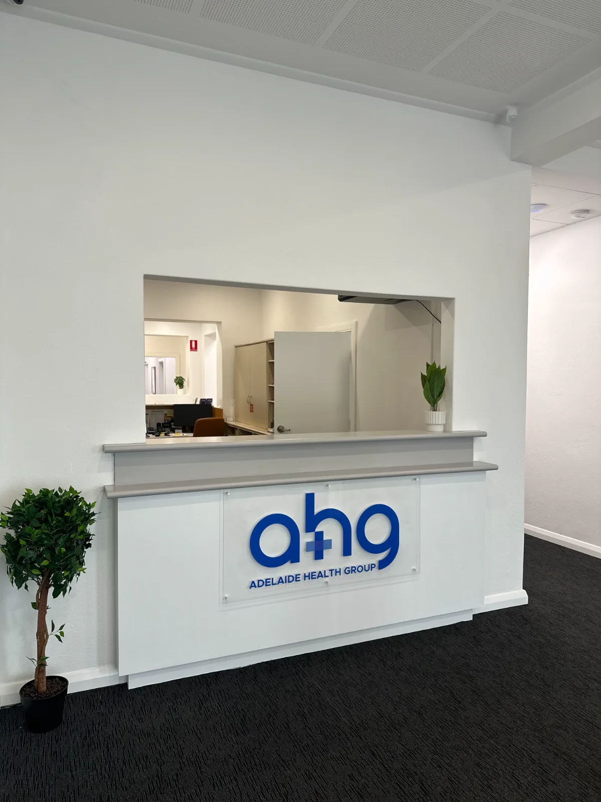 The reception counter at Adelaide Health Group, with the practice logo on the front panel